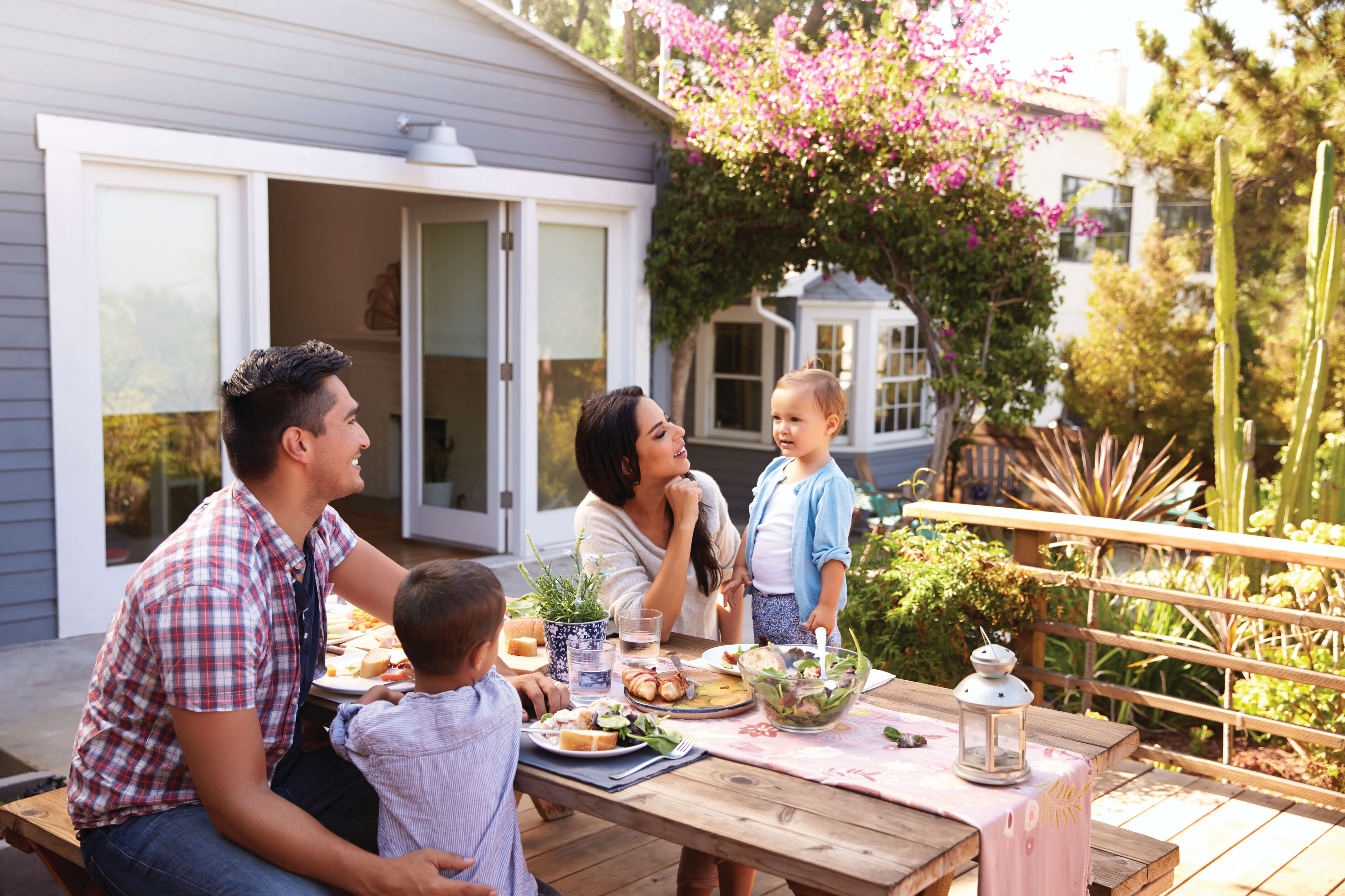 Family At Home Eating Outdoor Meal In Garden Together