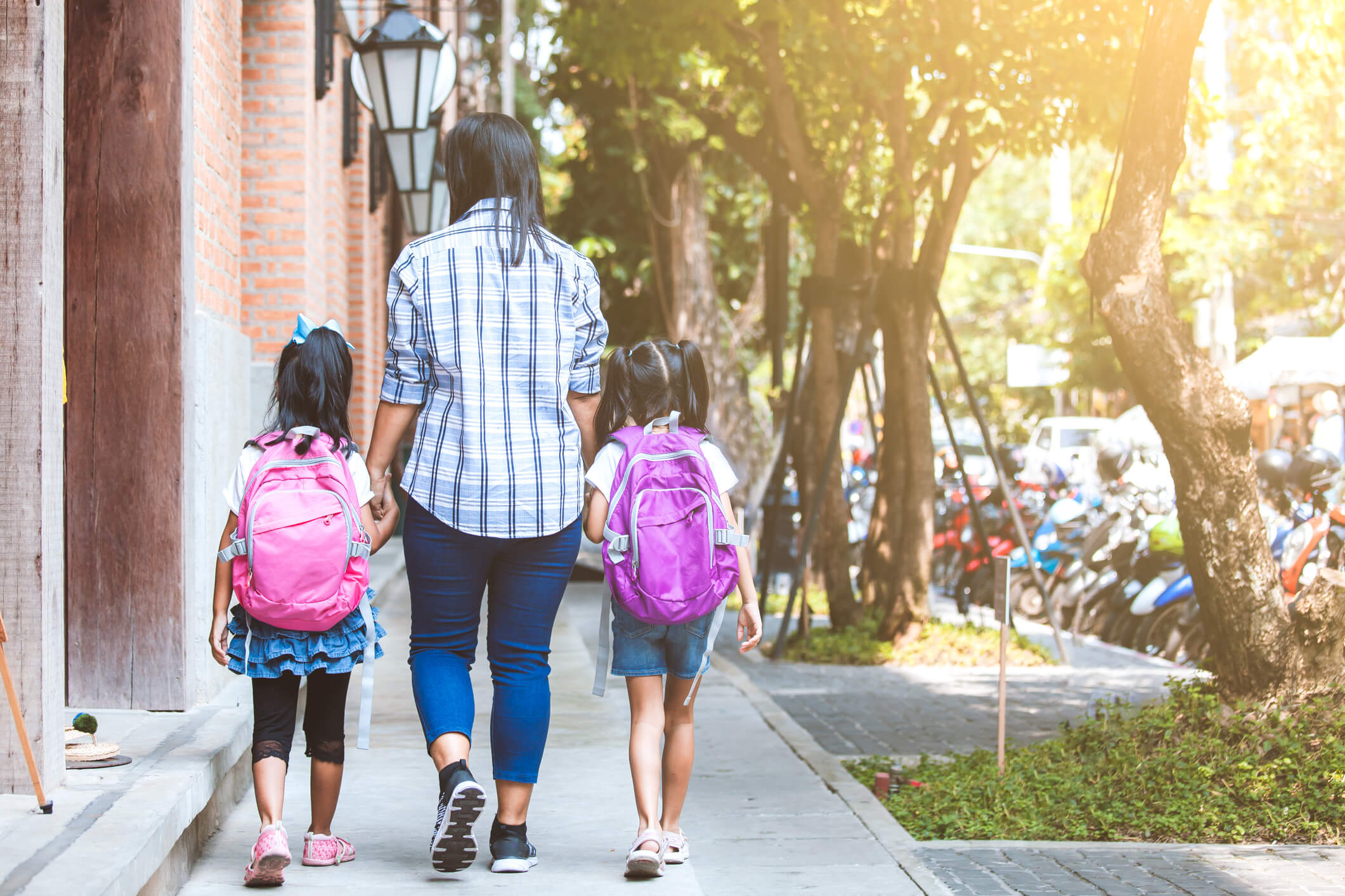 Asian mother and daughter pupil girl with backpack holding hand and going to school together