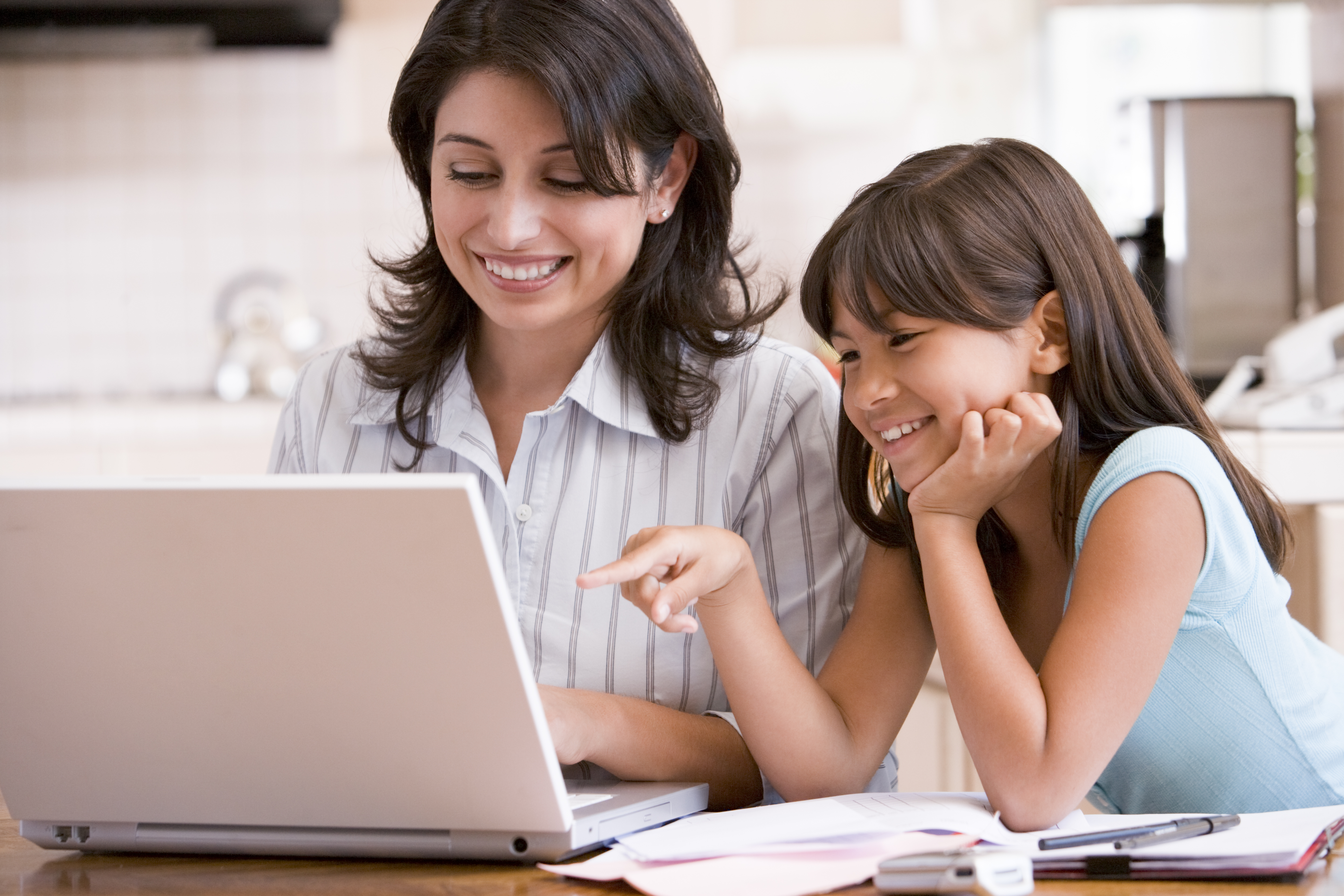 Woman and young girl in kitchen with laptop