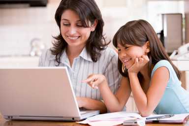 Woman and young girl in kitchen with laptop