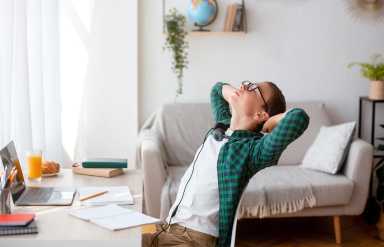 Sleepy schooler sitting in front of laptop and stretching