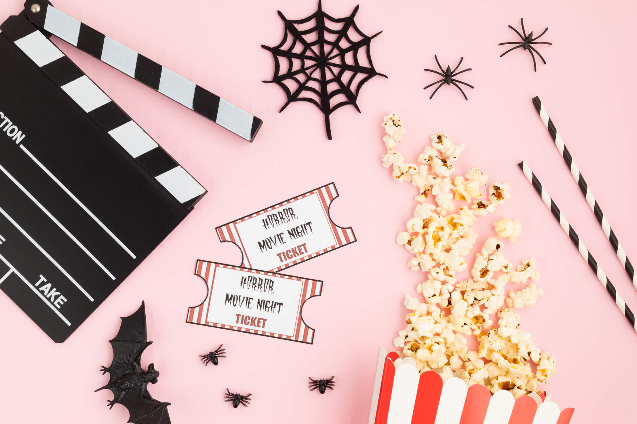 Movie clapperboard and halloween decoration over pink background