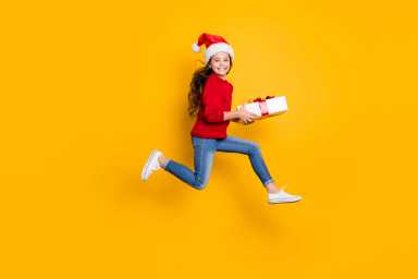 Full size profile photo of crazy little lady jumping high taking giftbox from santa in x-mas midnight wear red knitted pullover and jeans isolated yellow background