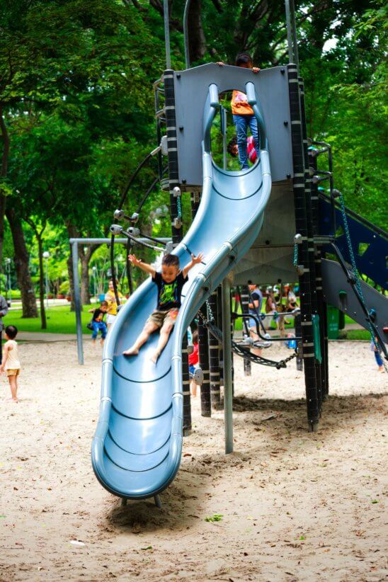 Kid on a slide at one of the inclusive playgrounds