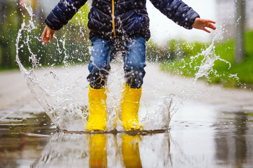 kid splashing in puddle on a rainy day