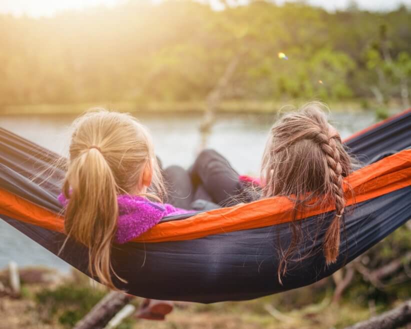 Two girls sitting in a hammock at one of the family campgrounds