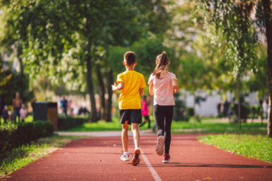 Child fitness, twins kids running on stadium track in city park , training and children sport healthy lifestyle. Outdoor activities by running make the child’s body healthy and experience enriched
