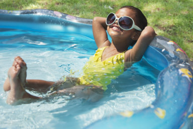 Hispanic girl relaxing in kiddie pool