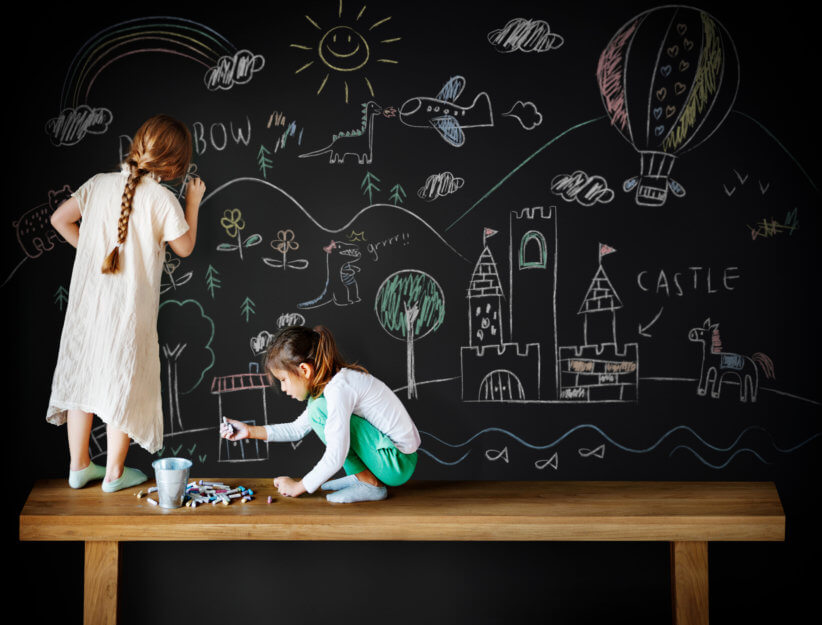 kids writing on a chalkboard wall