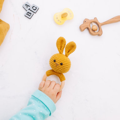 Kids hand holding bunny beanbag made from natural materials on marble background