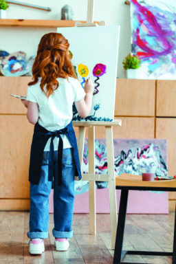 back view of redhead kid painting on canvas