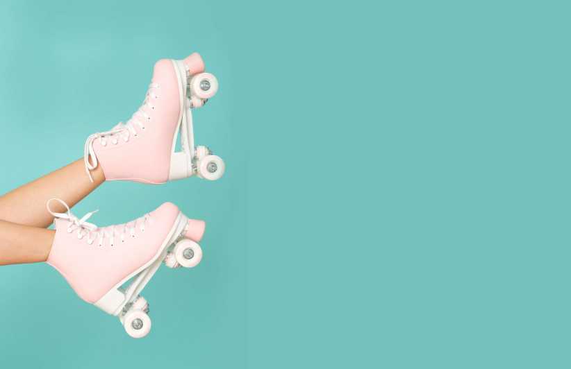 The image shows a pair of legs wearing light pink roller skates, raised playfully against a solid turquoise background.