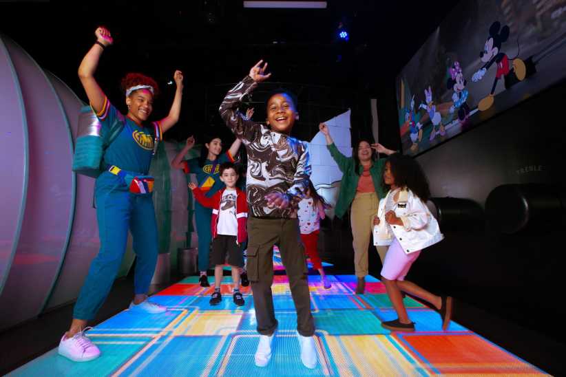 The file "DJ-Table-with-family-822x548.jpg" shows children and adults dancing on a colorful light-up floor, with Disney cartoon images projected on the wall in a playful, dark room.