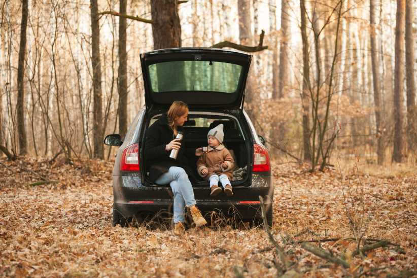 The file "GettyImages-1398328776-822x548.jpg" shows a woman and child sitting in the open trunk of a car, surrounded by a forest with autumn leaves.