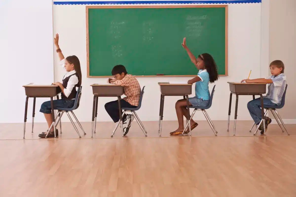 girls raising there hands in classroom