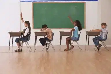girls raising there hands in classroom