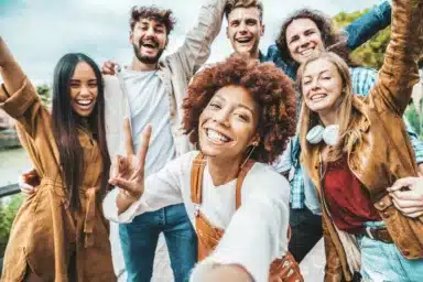 Happy multiracial friends taking selfie picture outside – Group of young people smiling together at camera outdoors – Teenagers having fun walking on city street – Youth culture and friendship concept