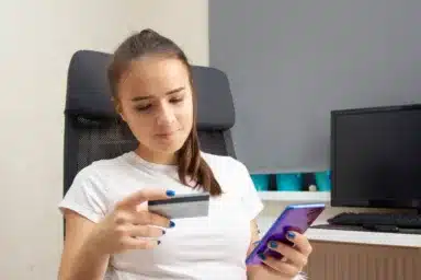 Young girl makes purchases with a credit card via smartphone