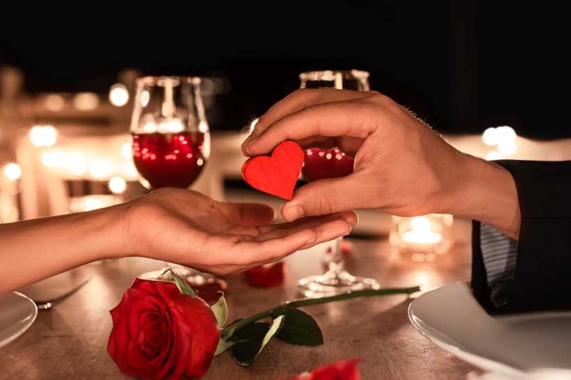 Man giving a heart to a woman on a romantic Valentines day dinner date.