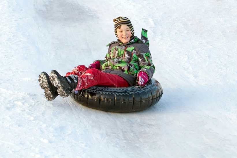 Child smiling sitting while snow tubing out in the snow in Westchester