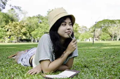 girl reading book on grass