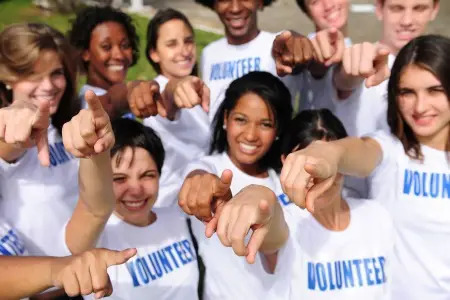 Group of Volunteers pointing towards the Camera