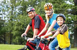 family biking together; parents and son riding bikes; bicycling; family wearing bike helmets