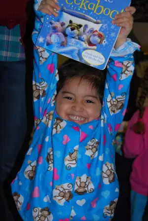 Young boy in pajamas holding up book