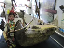 A young dance competitor poses next to an exhibit of a dug-out canoe aboard the EnviroMedia Mobile