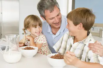 happy family; dad and two small children eating breakfast at the table together