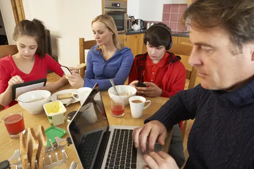 Family on their computers and cell phones at the dinner table