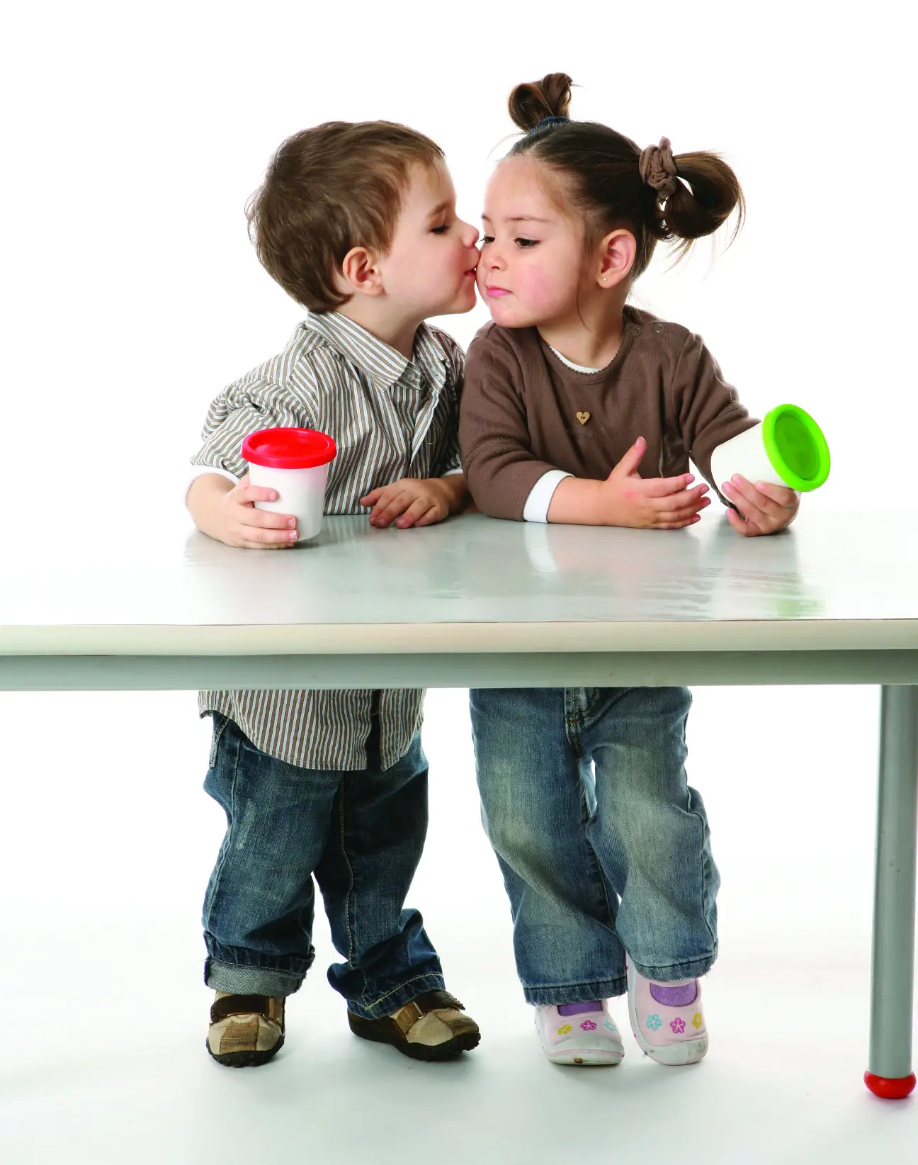 A young boy and girl kissing at a desk