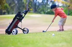 young boy playing golf; little boy hitting golf ball