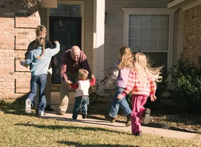 kids running to greet grandparents; grandparents greeting grandchildren; family visit