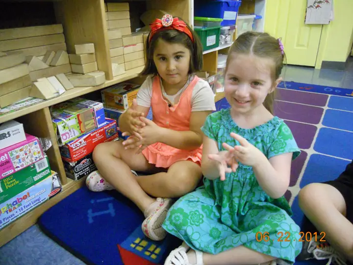 Two preschool girls at The Growing Tree Nursery School show their American Sign Language Skills.