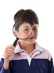 child holding a magnifying glass; young boy playing detective