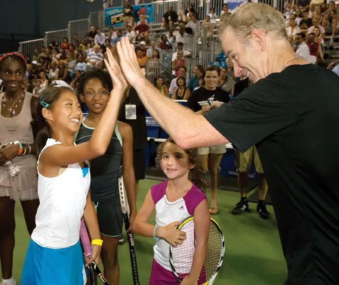 John McEnroe high-fives student at his tennis academy try outs.