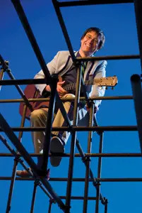 Justin Roberts on jungle gym, with guitar