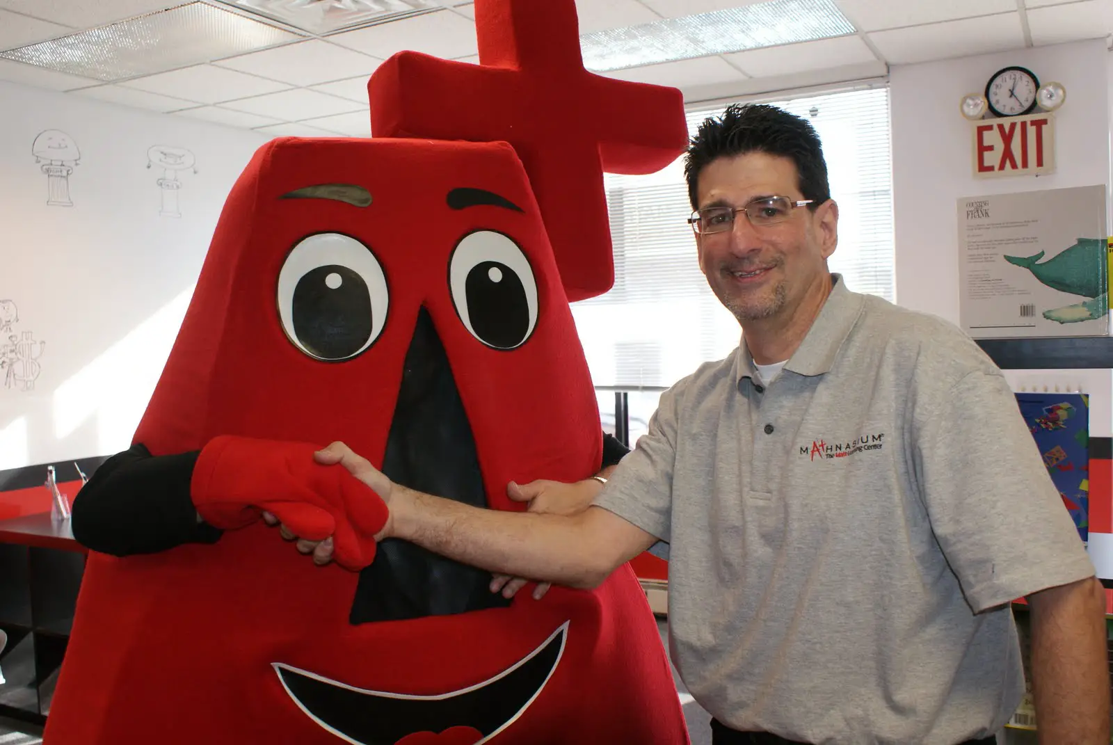 Mathnasium of New Hyde Park center director Peter Abrams greets mascot A+ at  the grand opening on January 16.