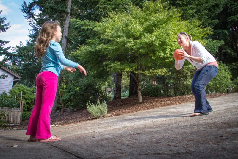 Researcher Megan MacDonald practices throwing a ball with a young girl.