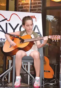 New York Guitar Academy; young girl playing an acoustic guitar