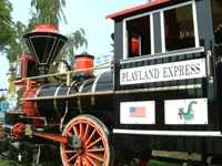 A black and red miniature steam locomotive named "Playland Express" featuring an American flag and a green dragon logo.