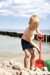 little boy digging in the sand at the beach; young boy playing at the beach