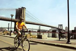 bicycle rider in front of Brooklyn Bridge; man riding a bike in Brooklyn