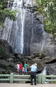 family poses at a waterfall for a photo in San Juan, Puerto Rico