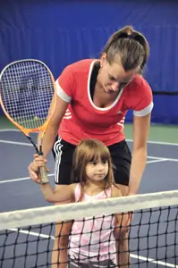 tennis instructor teaching little girl to play tennis