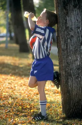 young soccer player drinking a sports drink