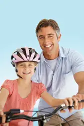 father teaching daughter how to ride a bike; dad and daughter biking, riding bikes