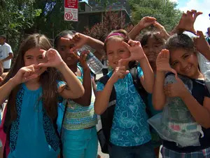 Children from Children's Aid Society doing the Super Power 'S' sign.