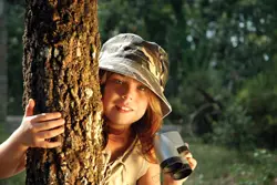 Survive: An Alternate Reality Game; little girl in camoflauge in woods, holding binoculars